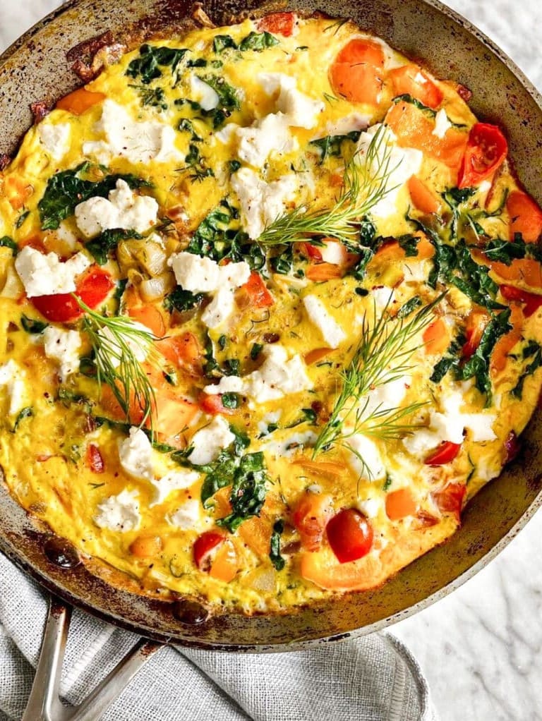 Birds eye view of the cooked frittata still in the skillet. Garnished with fronds of fresh dill. 