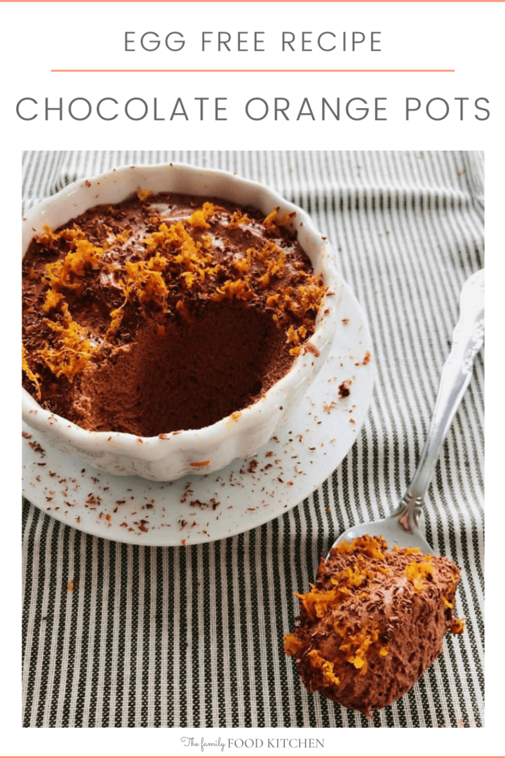 Pinnable image with recipe title and a teacup filled with chocolate mousse set on a saucer with a teaspoon of chocolate mousse topped with finely grated orange zest.