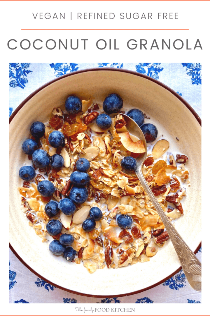 Pinnable image with recipe title and bowl of crunchy granola with chopped nuts and shredded coconut, topped with fresh blueberries.