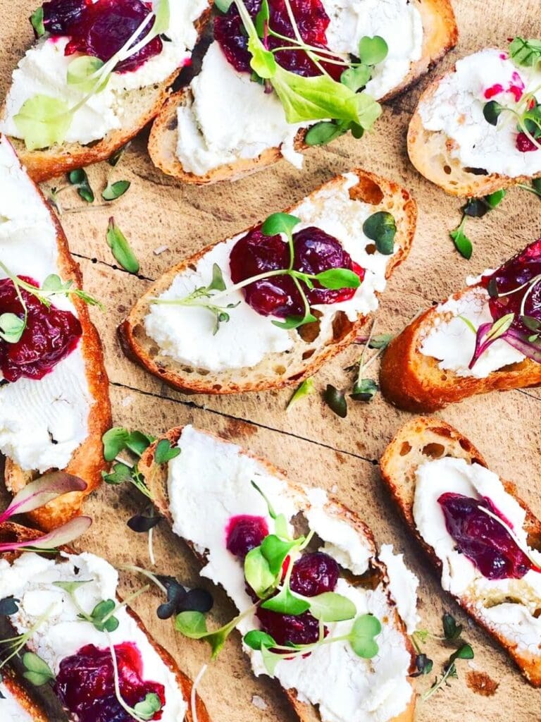 Overhead view of the finished toasts on a wooden board ready to be served. Microgreens are scattered as a garnish. 