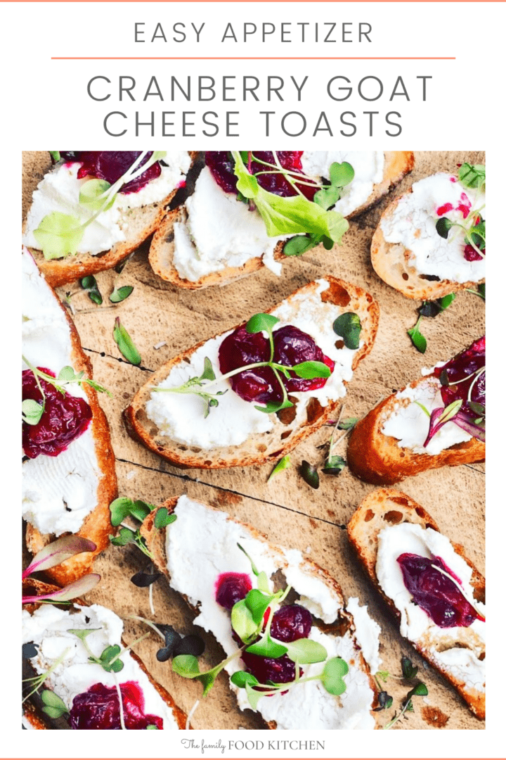 Pinnable image with recipe title and slices of toasted French bread topped with goats cheese and cranberry on a wooden board with microgreens scattered over.