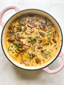 A Dutch oven filled with ground beef, mushroom and wild rice soup.