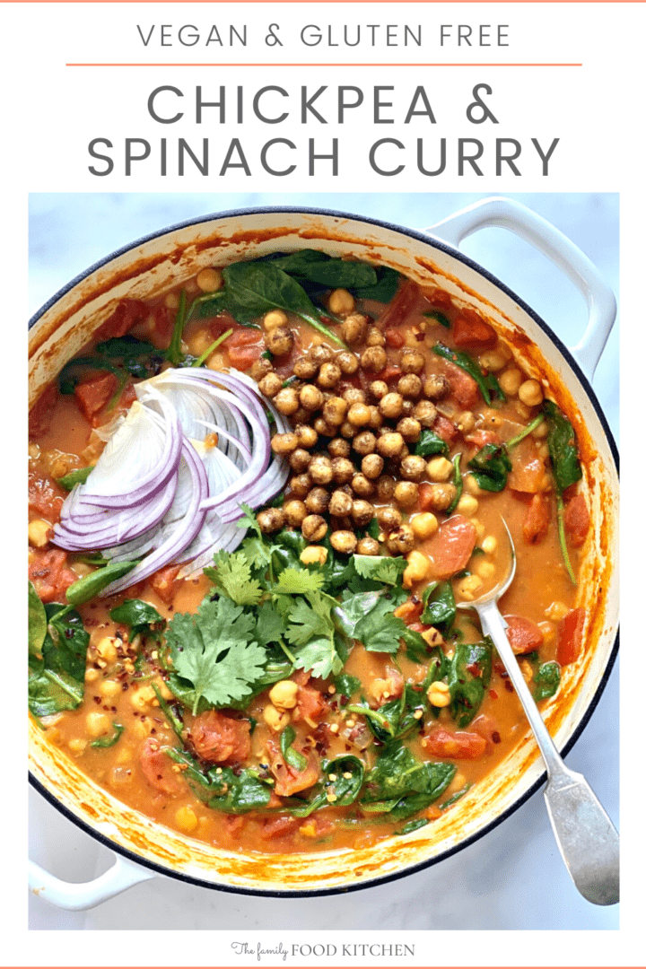 Pinnable image with recipe title and large pot containing chickpea and spinach curry, topped with roasted chickpeas, sliced red onion and fresh cilantro leaves.