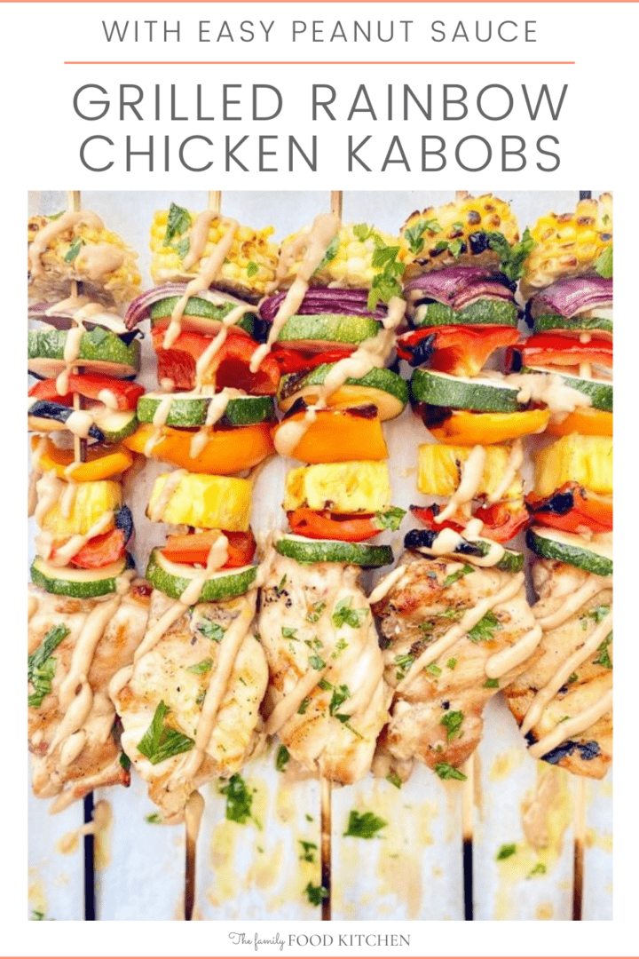 Pinnable image with recipe title and cooked and charred chicken thigh kebabs with zucchini, peppers, pineapple, onion and corn on skewers and drizzled with peanut sauce.