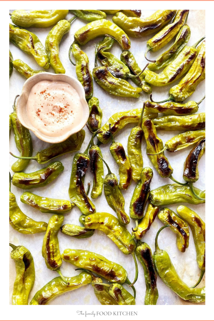 Pinnable image with recipe title and cooked and blistered peppers shown on sheet pan with dipping sauce.