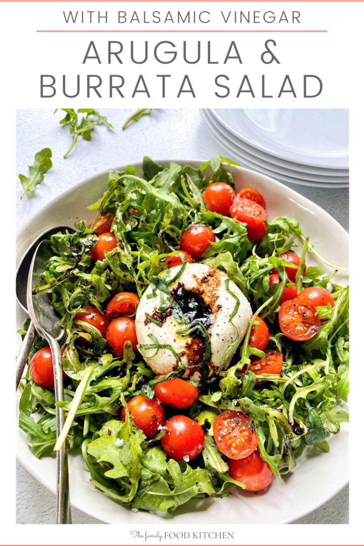 Pinnable image with recipe title and top down image of white bowl filled with arugula and cherry tomato salad, topped with a ball of burrata cheese and drizzled with olive oil and balsamic dressing.