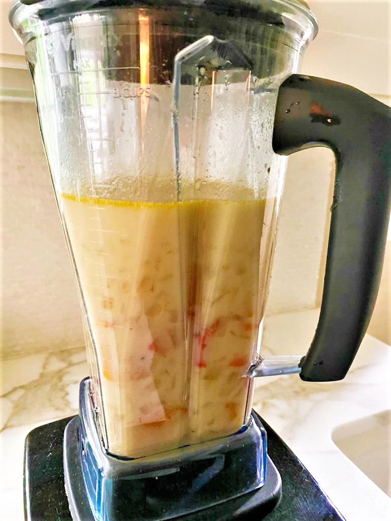 Blender containing cooked soup being blitzed to smooth