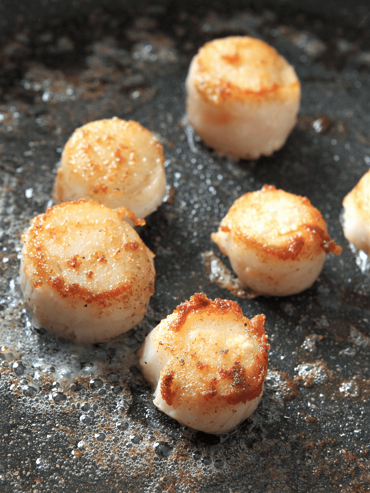 Scallops being seared in a cast iron skillet