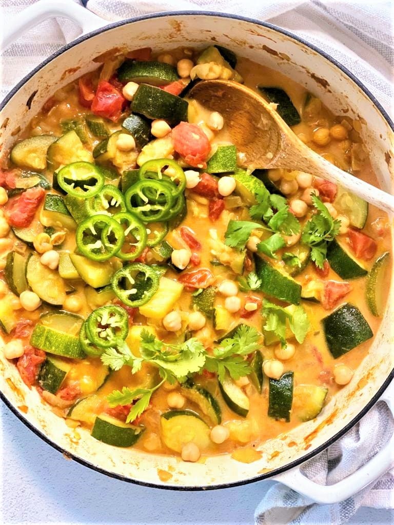 Pan containing cooked zucchini curry topped with a scattering of freshly chopped green chilies and cilantro.