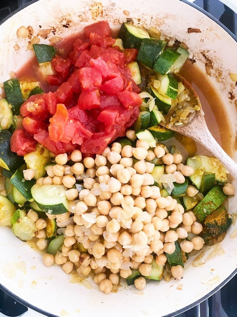 Zucchini curry being cooked in pan with added chickpeas and canned chopped tomatoes