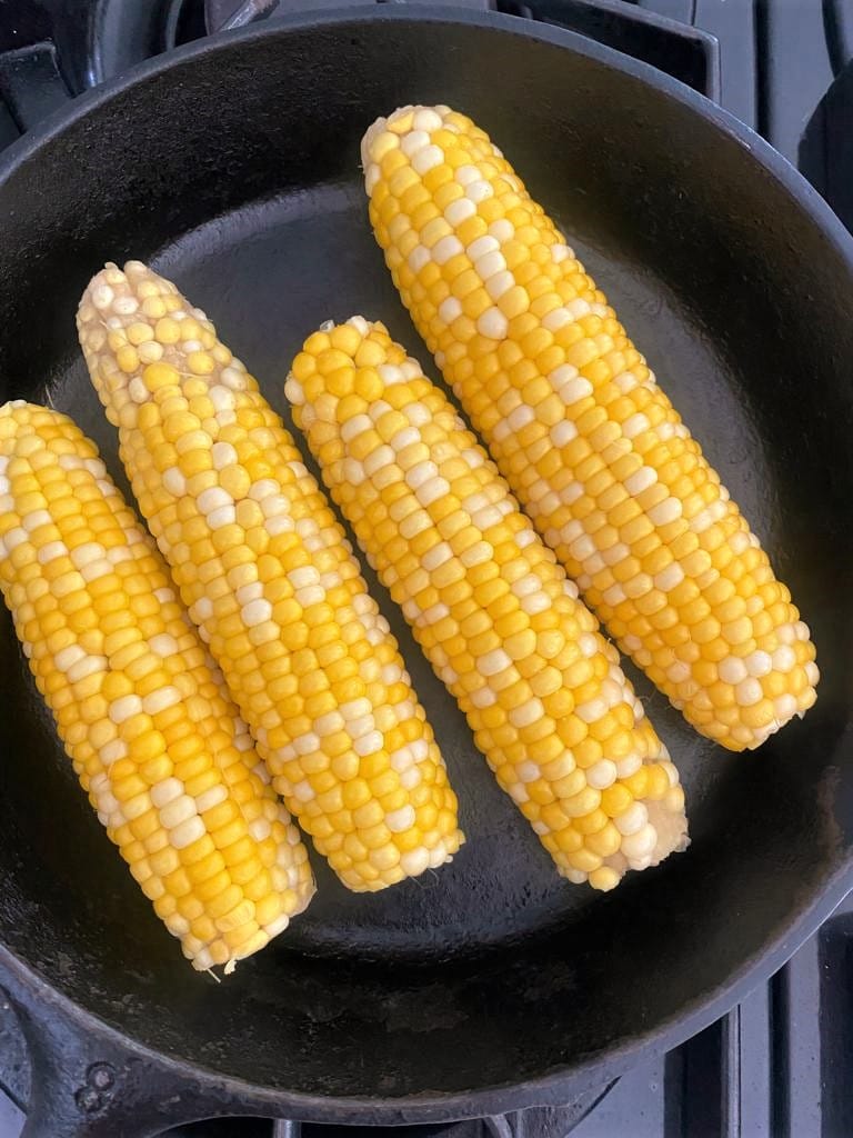 Boiled ears of corn set into a cast iron skillet