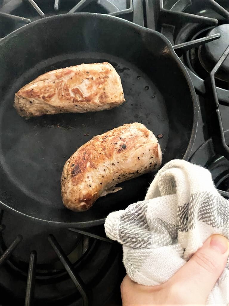 Pork tenderloin seared to golden brown  on the stove top in a cast iron skillet
