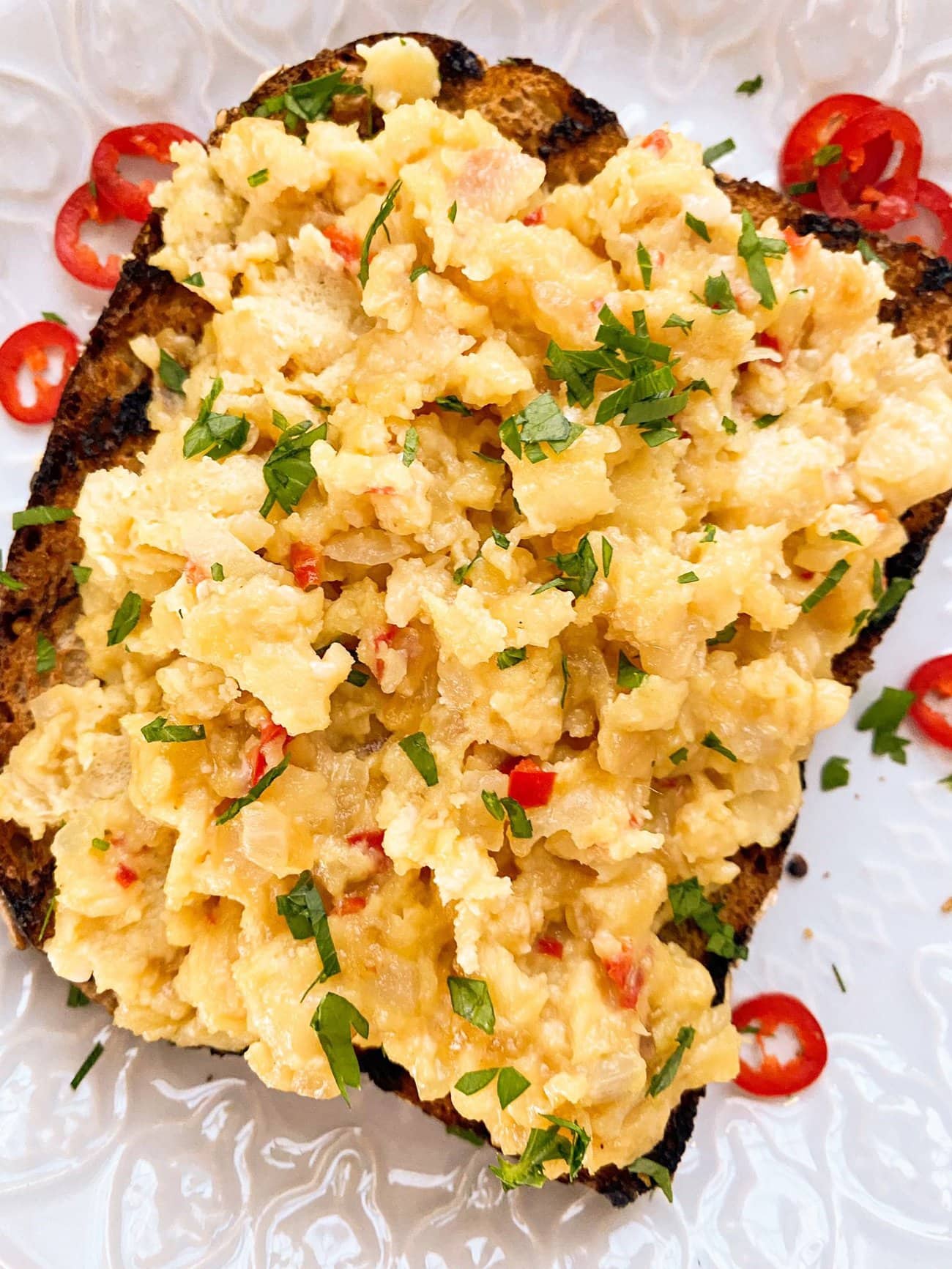 Chili scrambled eggs served on top of a slice of toasted granary bread, garnished with fresh sliced red chili and chopped parsley