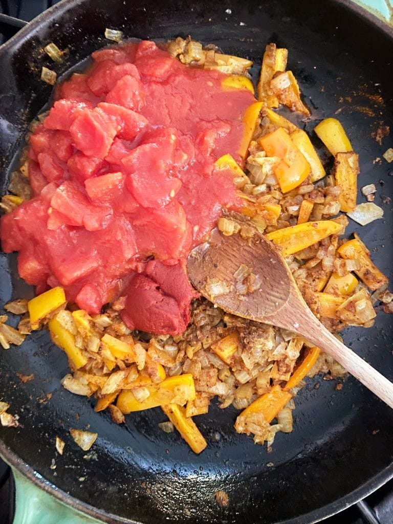 Cast iron skillet with sauteed vegetables and added canned chopped tomatoes 