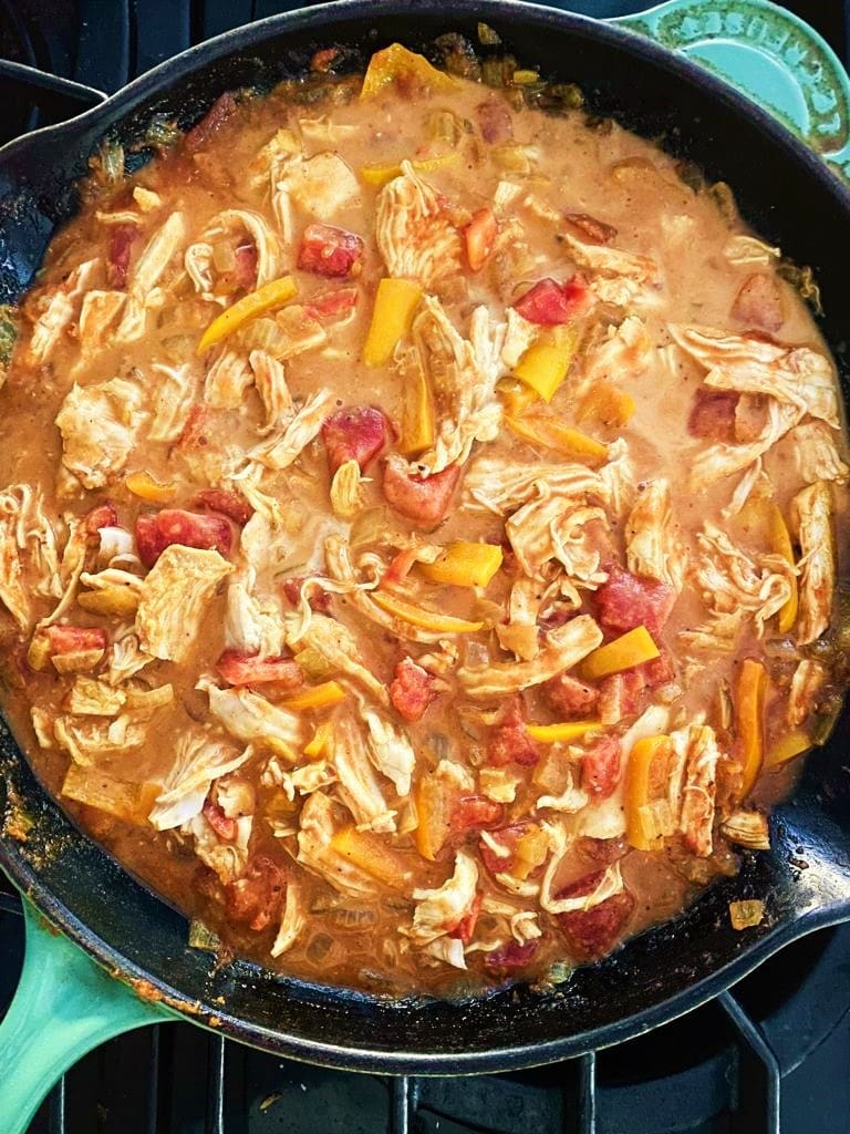 Leftover chicken curry with coconut milk cooking in a cast iron skillet