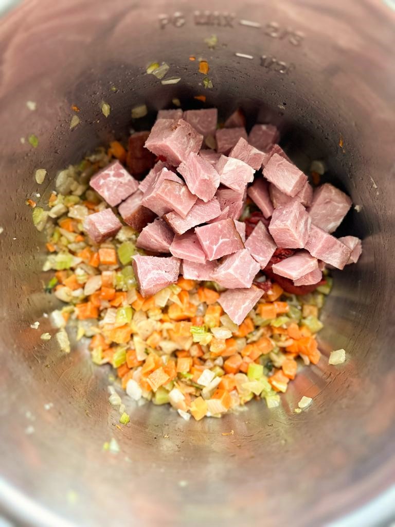Instant Pot filled with sauteed vegetables, tomato puree and large chunks of cooked ham