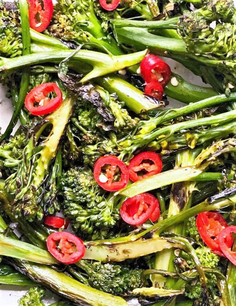 close up image of charred broccolini garnished with sliced red chili