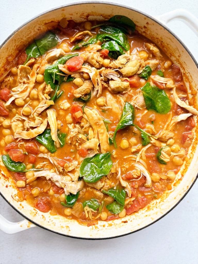 Dutch oven filled with chicken & chickpea curry with wilted spinach