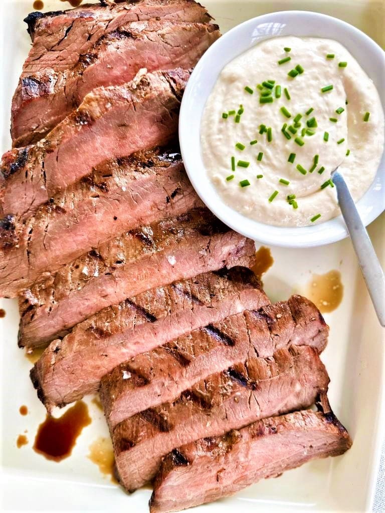 Plate of grilled beef with a bowl of horseradish aioli topped with freshly chopped chives