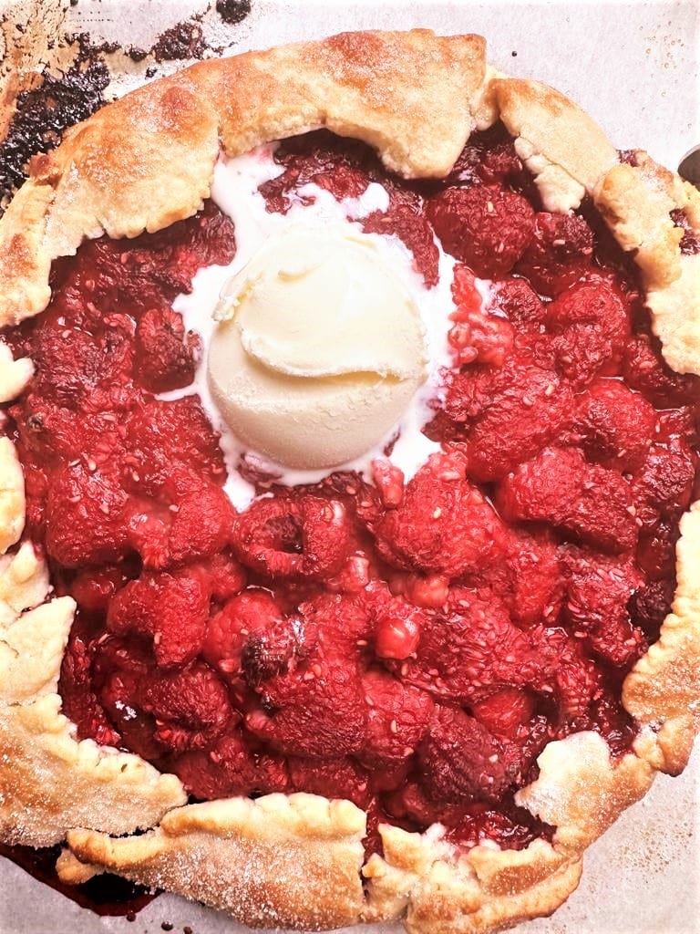 Rustic raspberry galette topped with a scoop of vanilla ice-cream