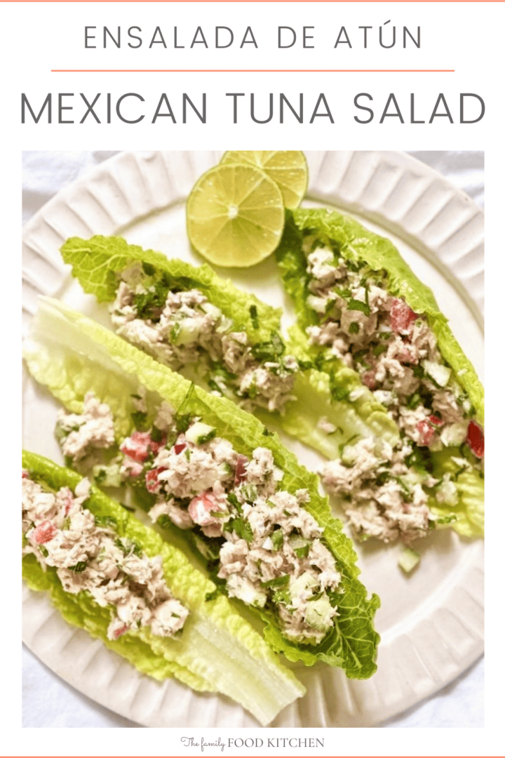 A pinnable image with recipe title and a white plate topped with Mexican tuna salad served in individual salad leaves with a wedge of lime set alongside.