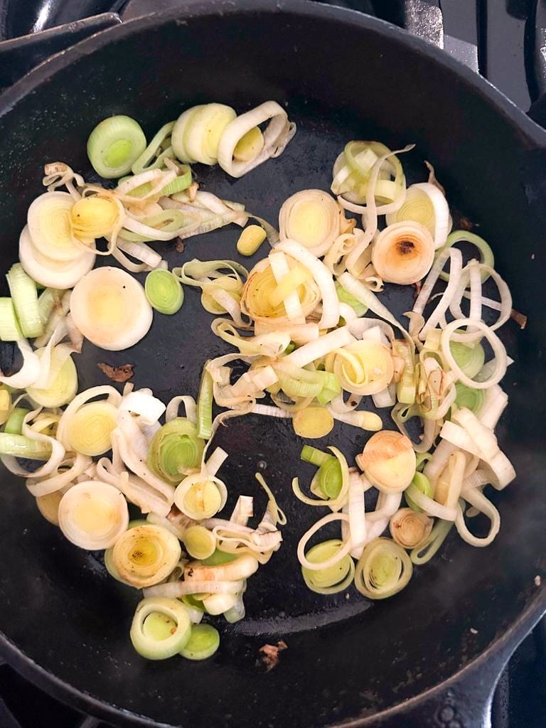 A skillet filled with sauteed sliced leeks.