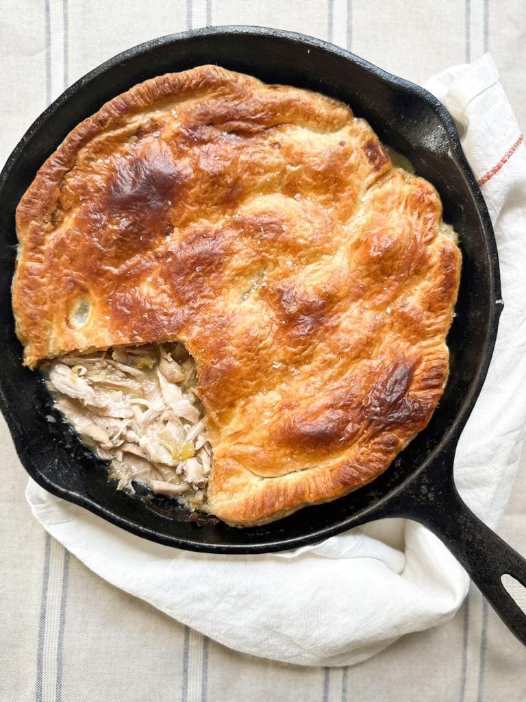 A skillet filled with cooked chicken and leek pot pie.