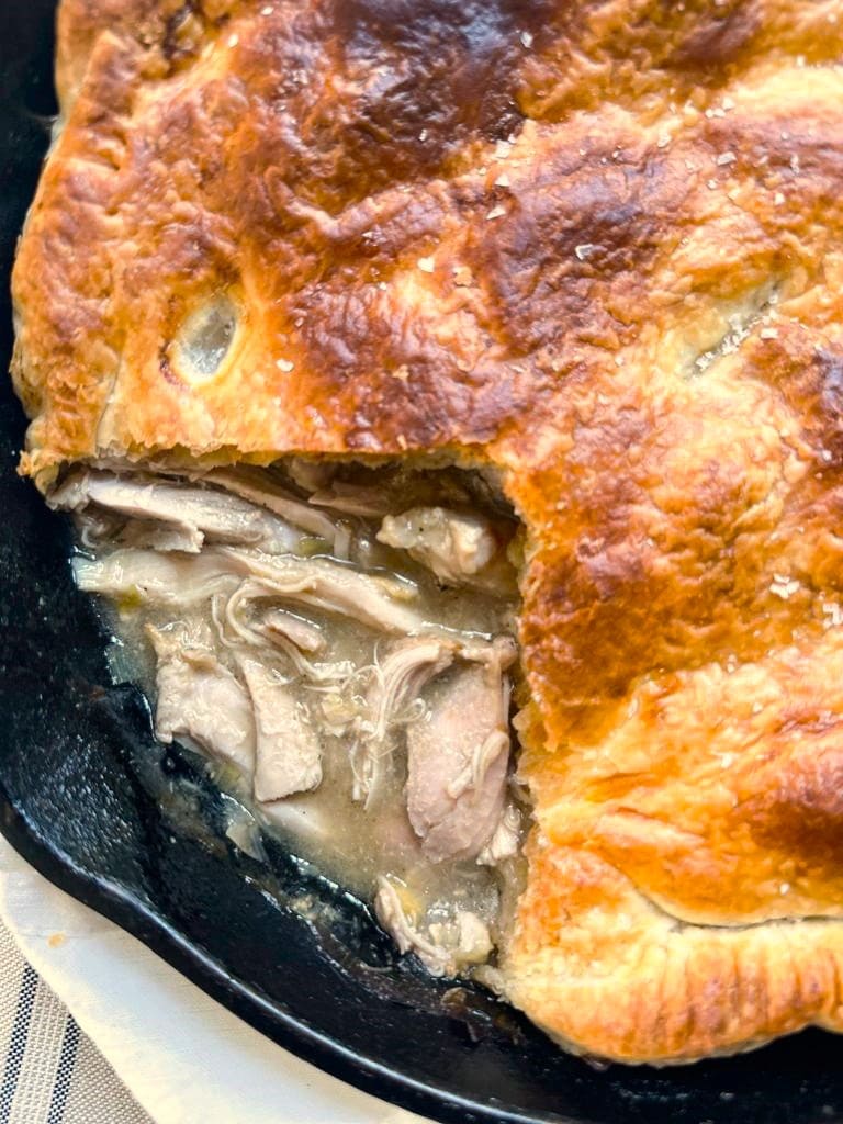 Close up image of a skillet filled with cooked chicken and leek pot pie.