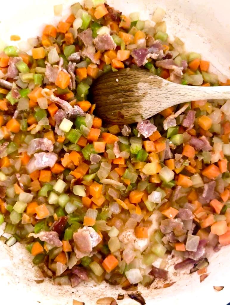 Dutch oven with sauteed bacon and diced carrot, celery, onion and garlic.