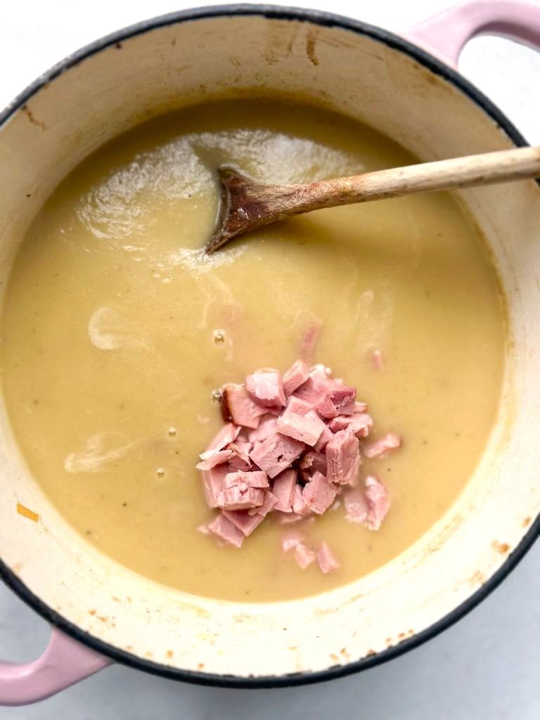 A Dutch oven filled with creamy leek and potato soup with added diced ham.