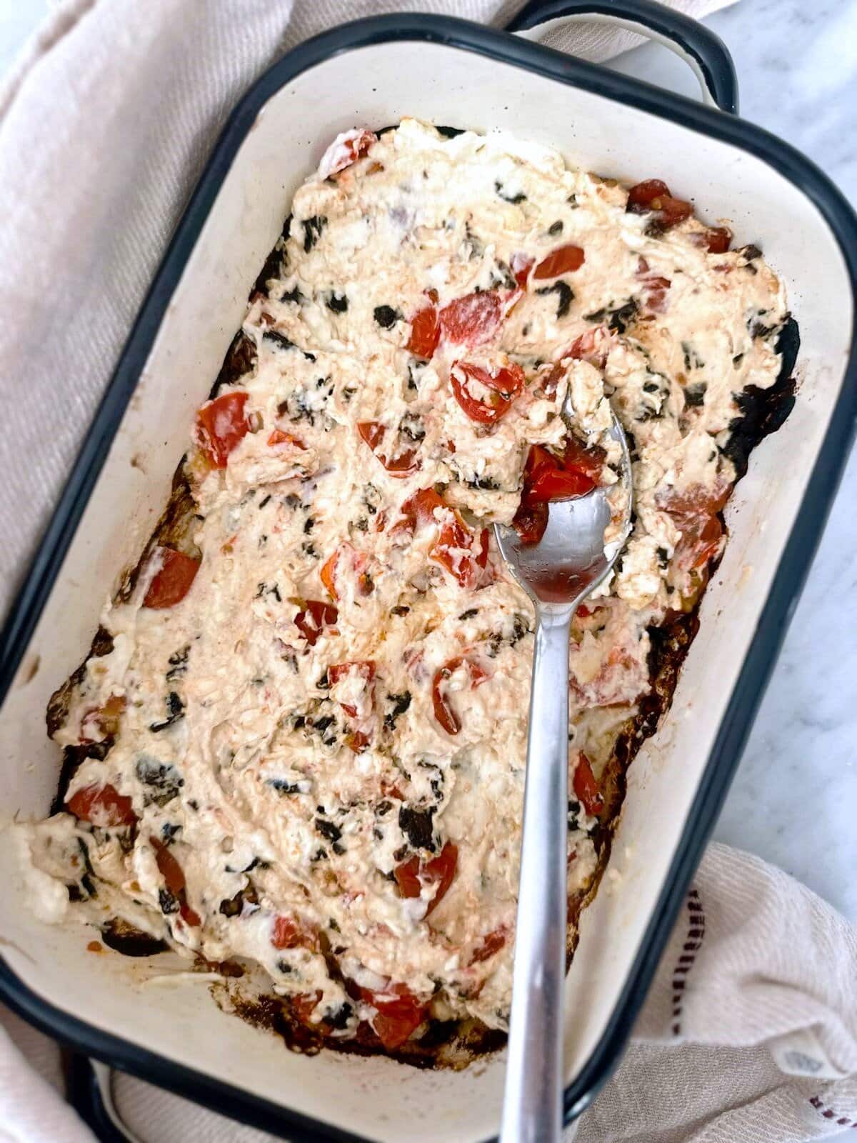 A shallow dish with hot baked feta cheese dip.