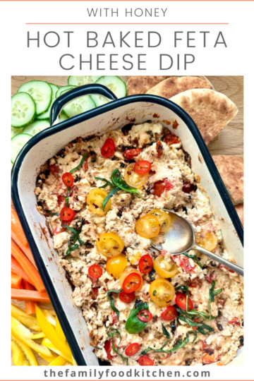 Pinnable image with recipe title and a shallow dish of hot baked feta cheese dip, topped with fresh tomatoes and shredded basil leaves.