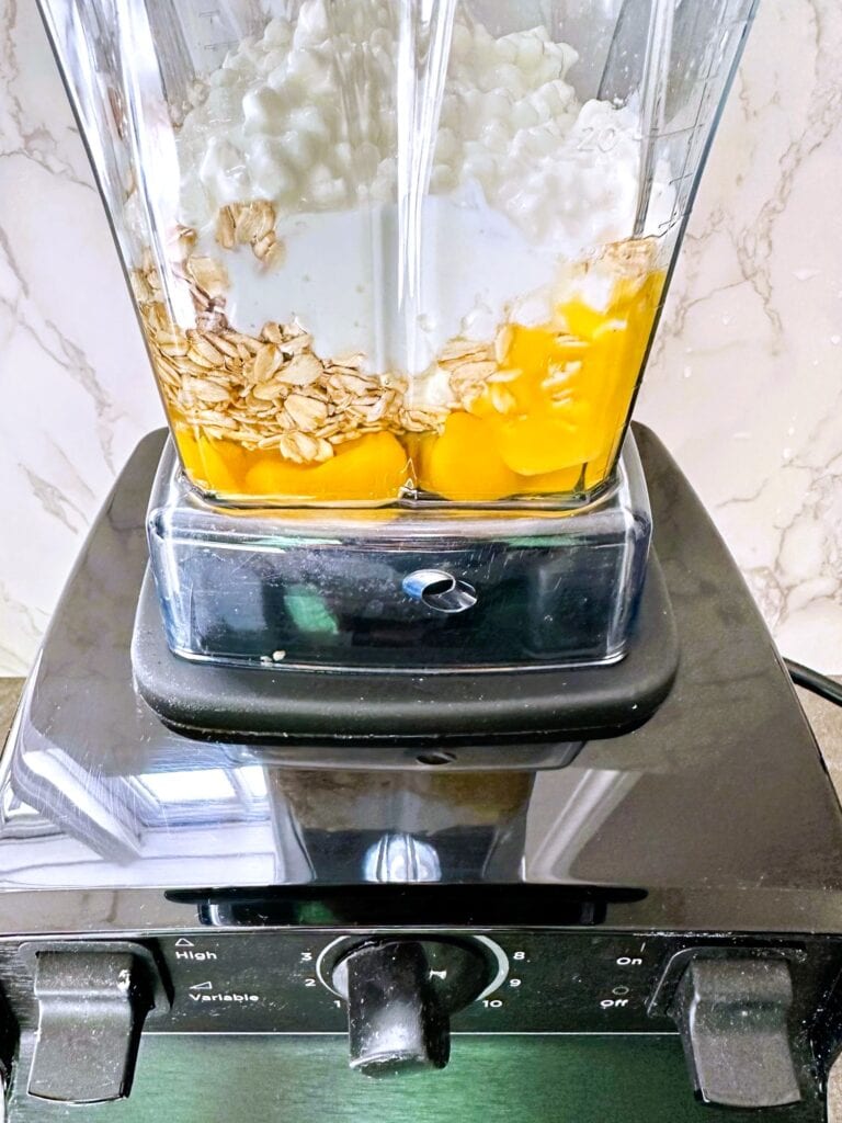 A blender containing rolled oats, eggs and cottage cheese.