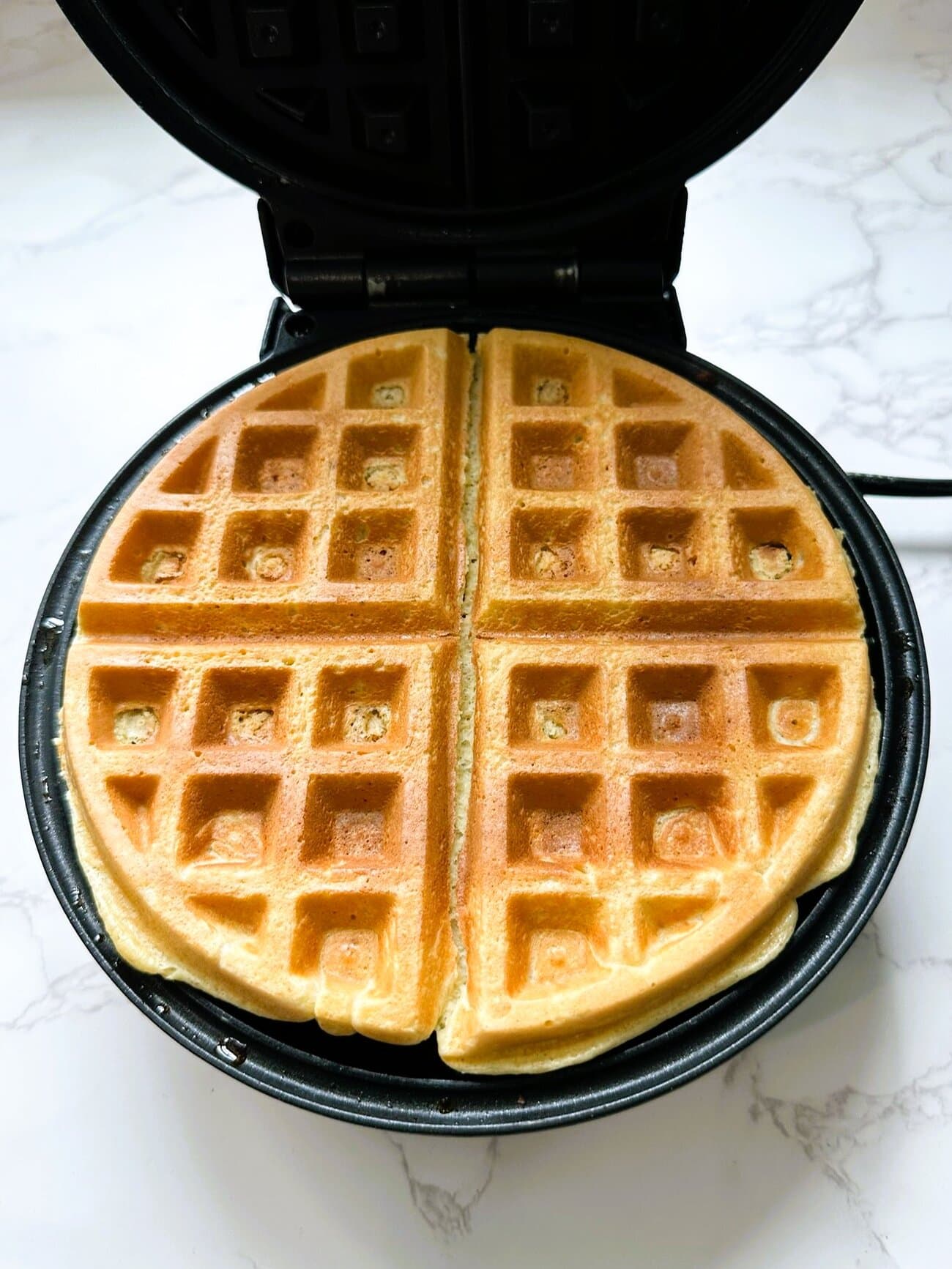 A waffle iron of golden cooked high protein waffles.