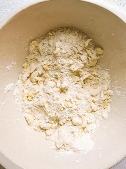 A mixing bowl of flour and sugar with butter rubbed through.