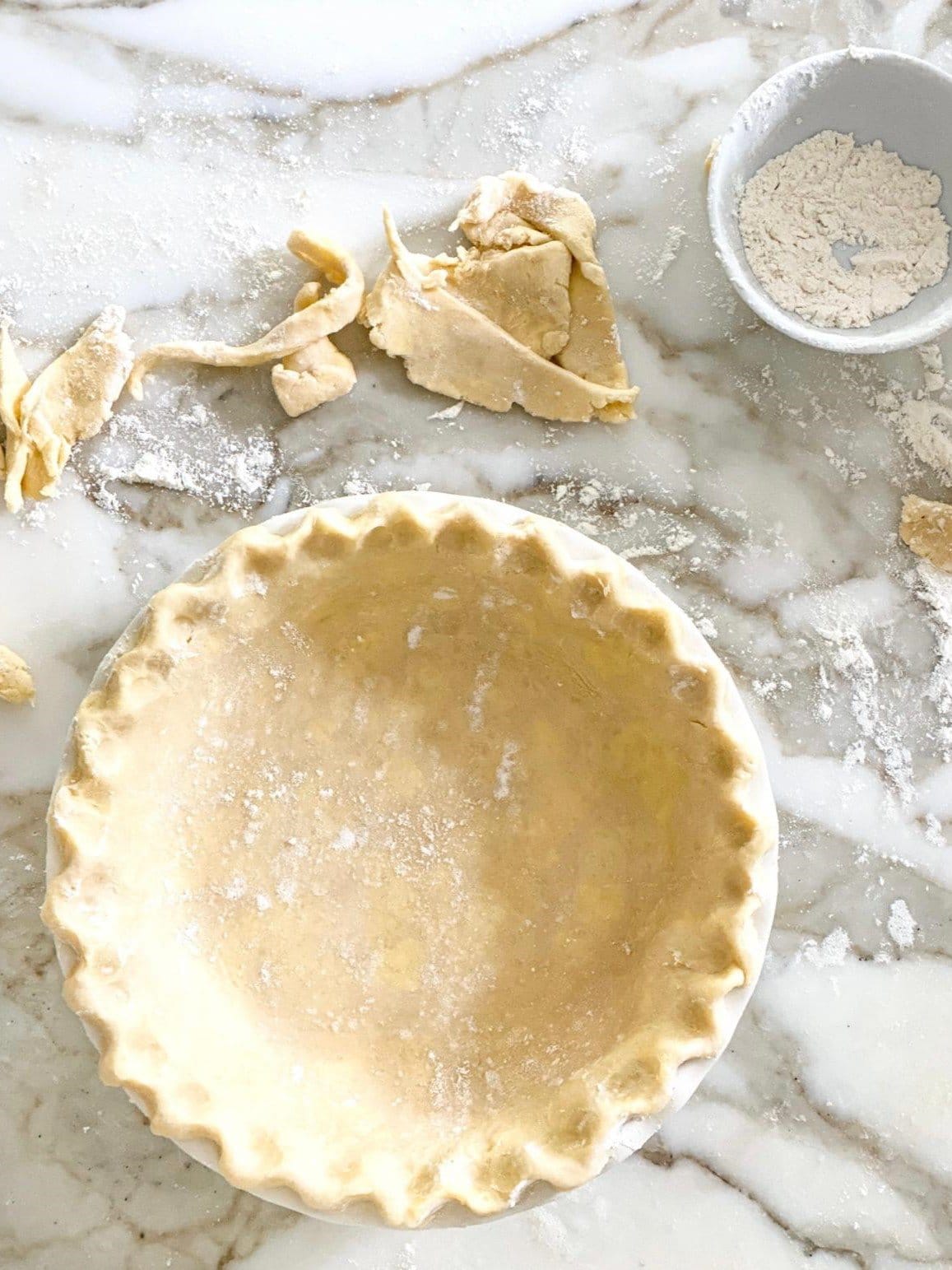 A pie dish filled with shortcrust pastry dough.