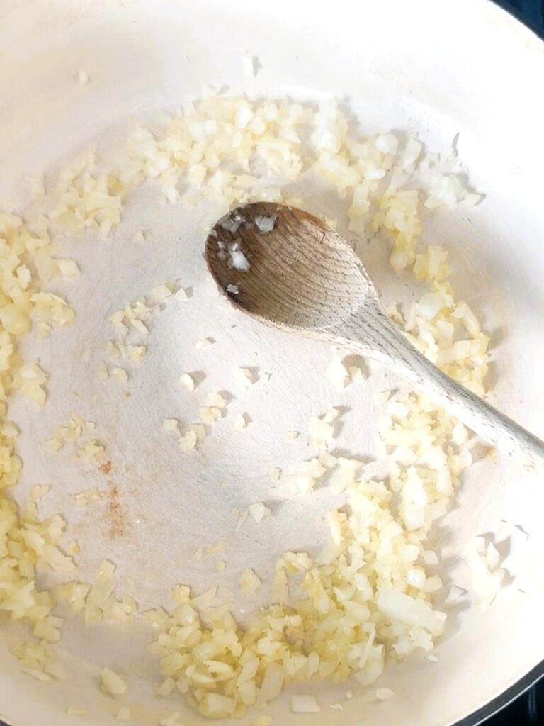 A large skillet with olive oil and sauteed onion and minced garlic.
