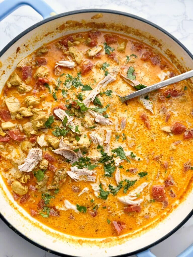 A Dutch oven of chicken tikka masala soup garnished with freshly chopped cilantro.