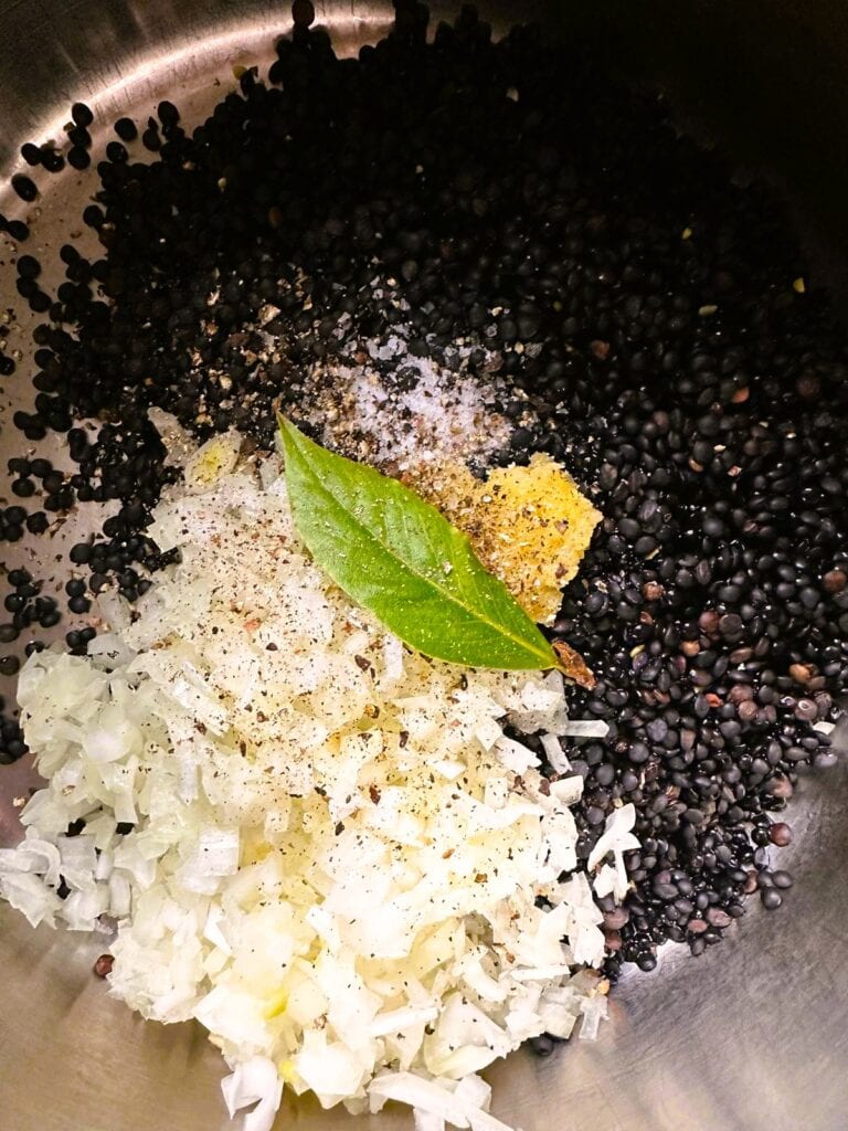 A large post of rinsed lentils, with diced onion, garlic and bay leaf.