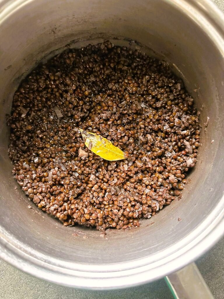 A large saucepan of cooked black lentils.