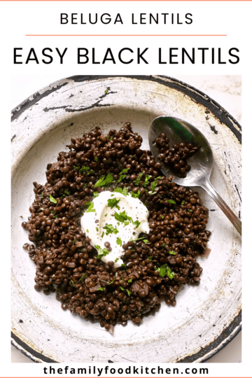 Pinnable image with recipe title and a bowl of black lentils (beluga lentils) topped with a spoon of thick Greek yogurt and a garnish of freshly chopped parsley.