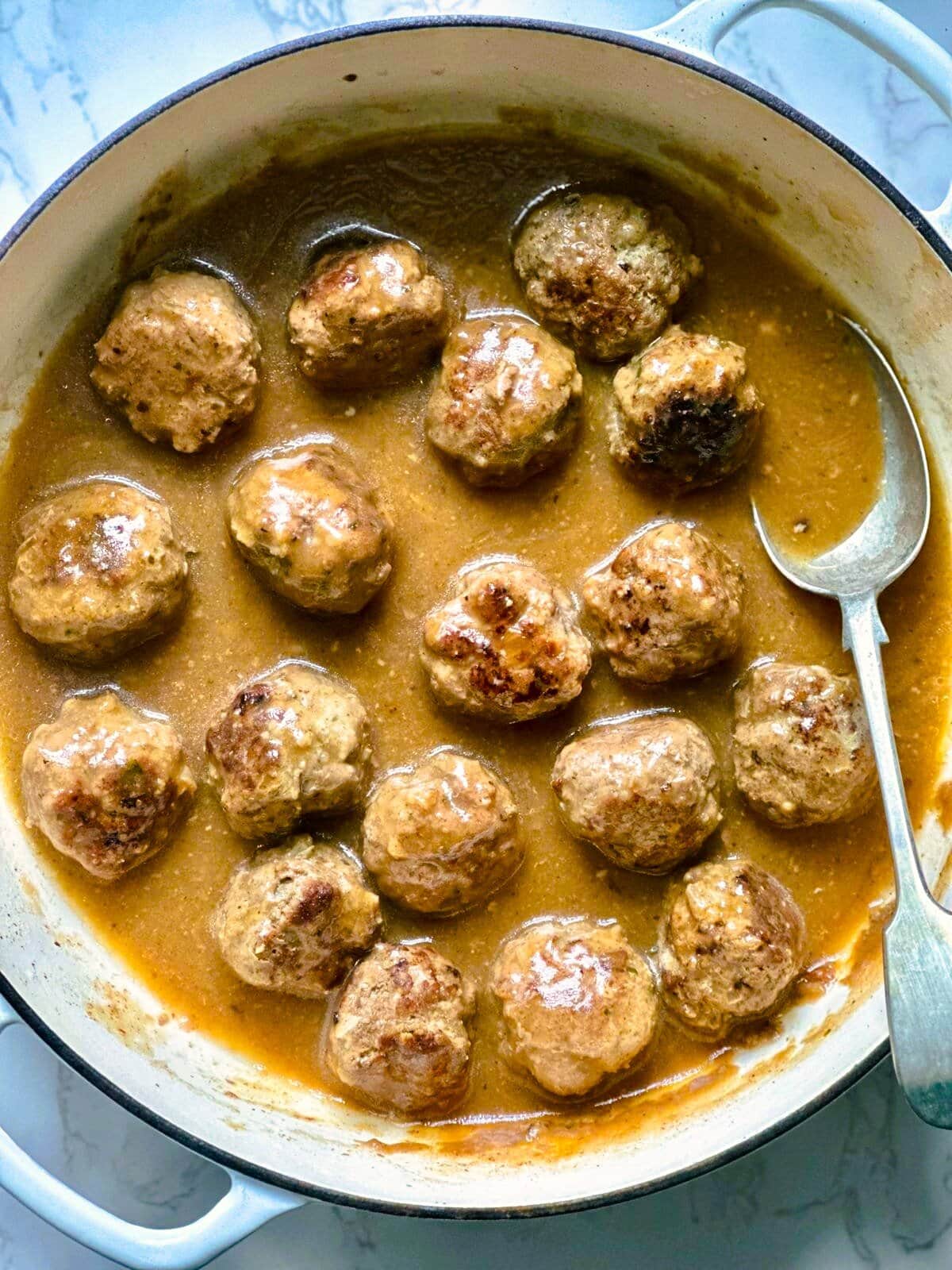 A Dutch oven of gluten-free meatballs in beef gravy.