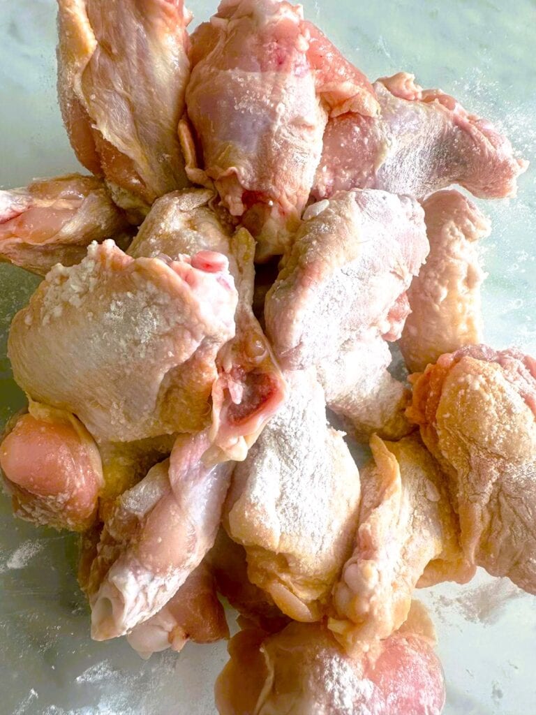 A bowl of raw chicken wings coated in baking powder, salt, pepper and garlic powder.