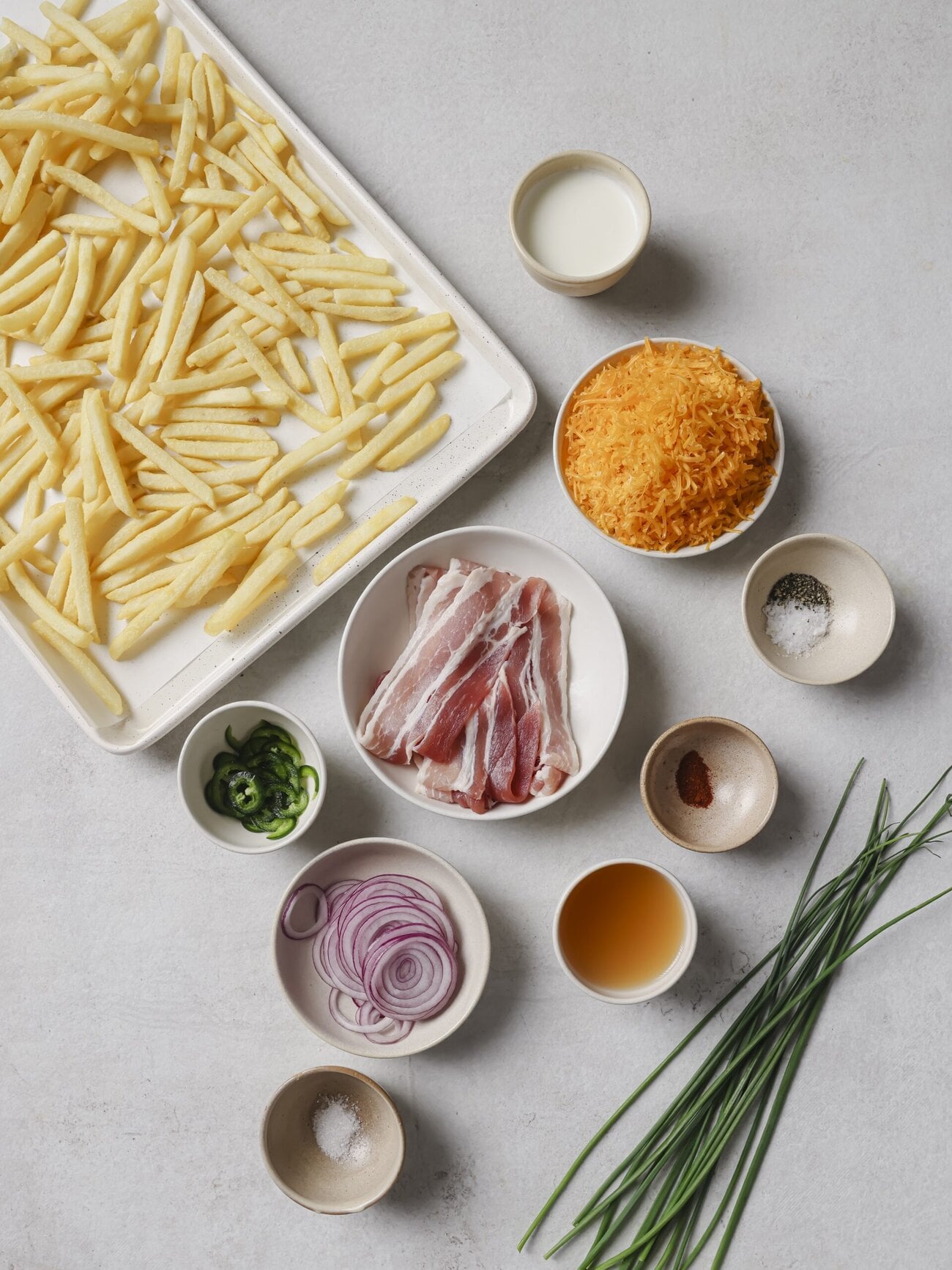Individual recipe ingredients for making bacon and cheese loaded fries.