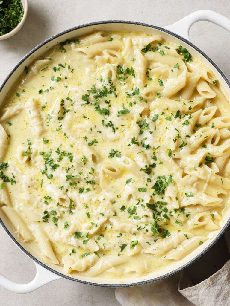 A large skillet of French onion soup pasta garnished with chopped parsley.