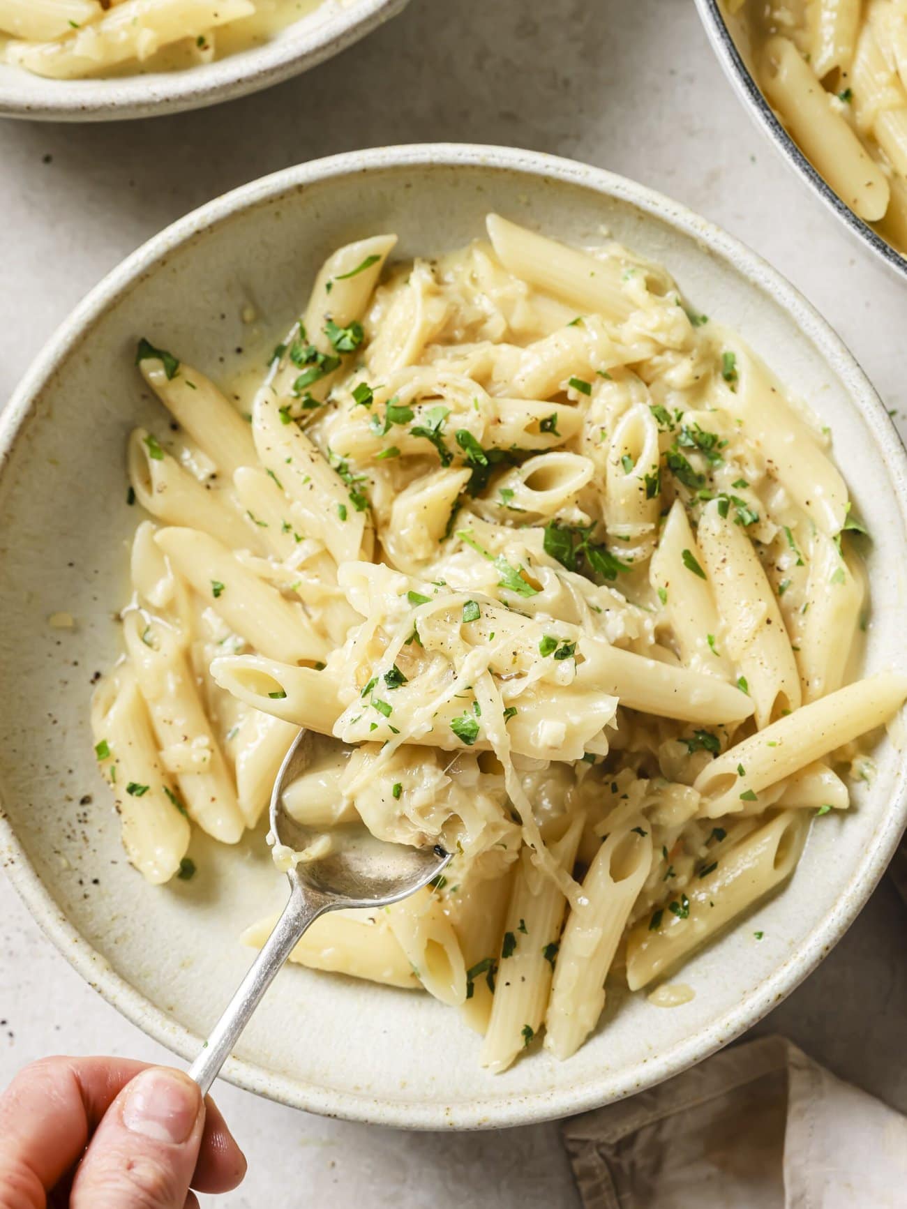 A bowl of cheesy French onion soup pasta garnished with freshly chopped herbs.