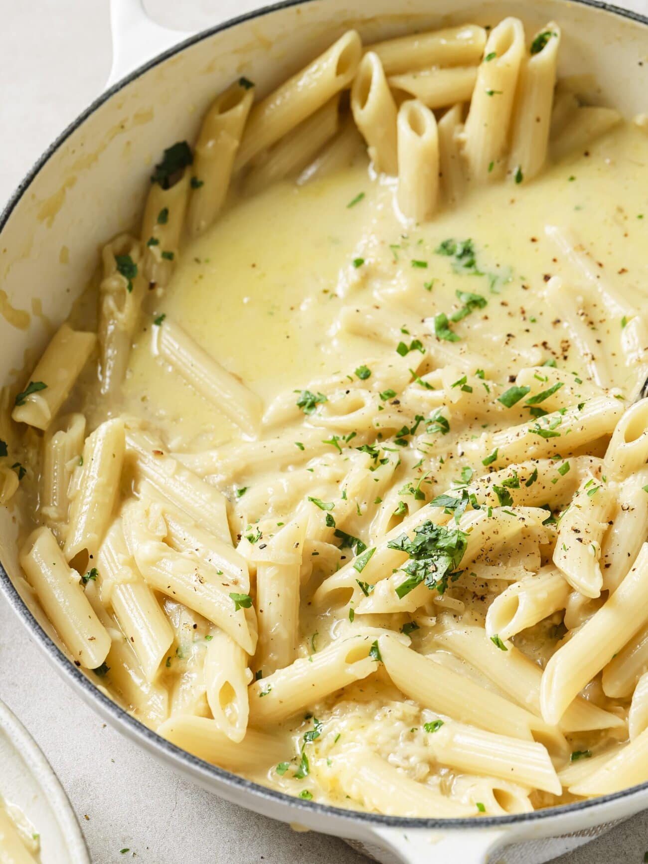 A large skillet of cheesy French onion soup pasta garnished with freshly chopped herbs.