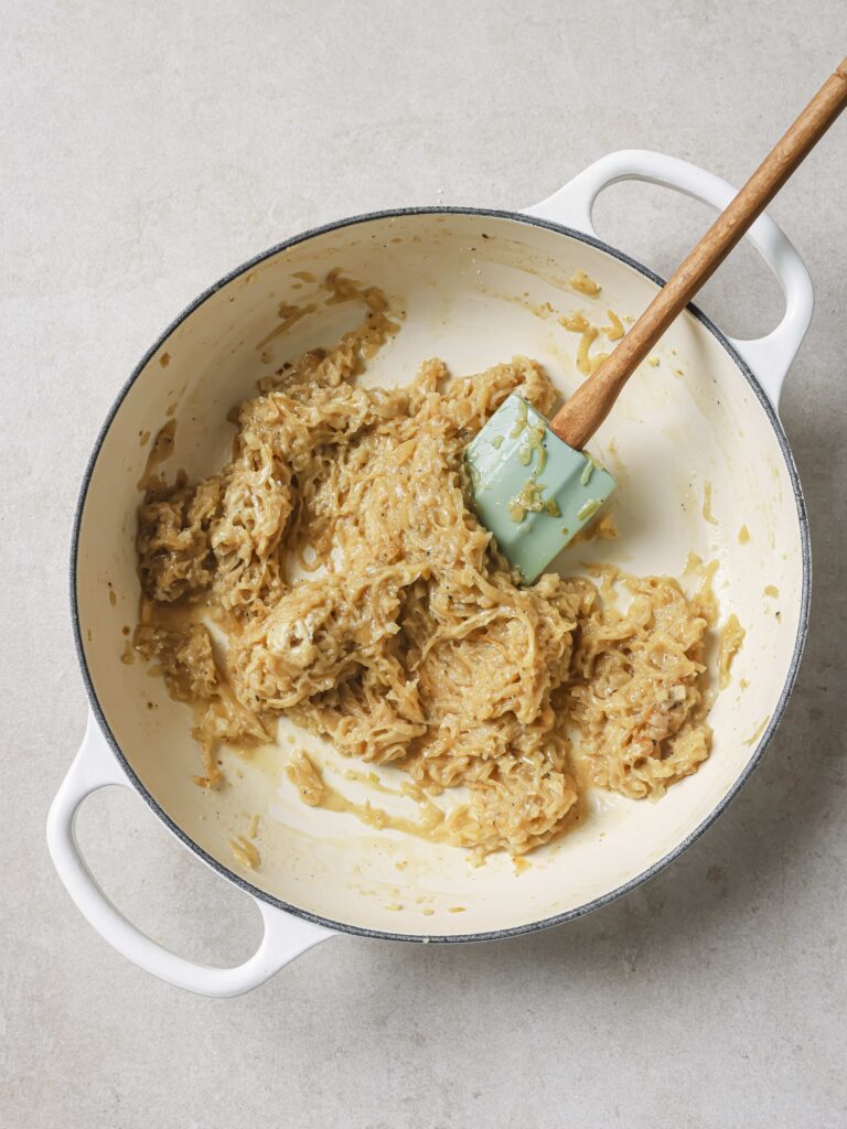 A large skillet of sauteed onions with added cornstarch.