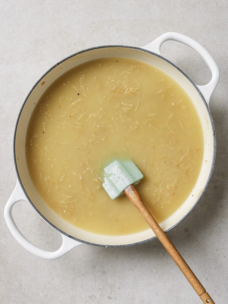 A large skillet of sauteed onions and garlic with added beef broth and Worcestershire sauce.