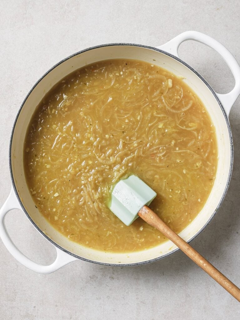 A large skillet of cooked onions with beef broth.